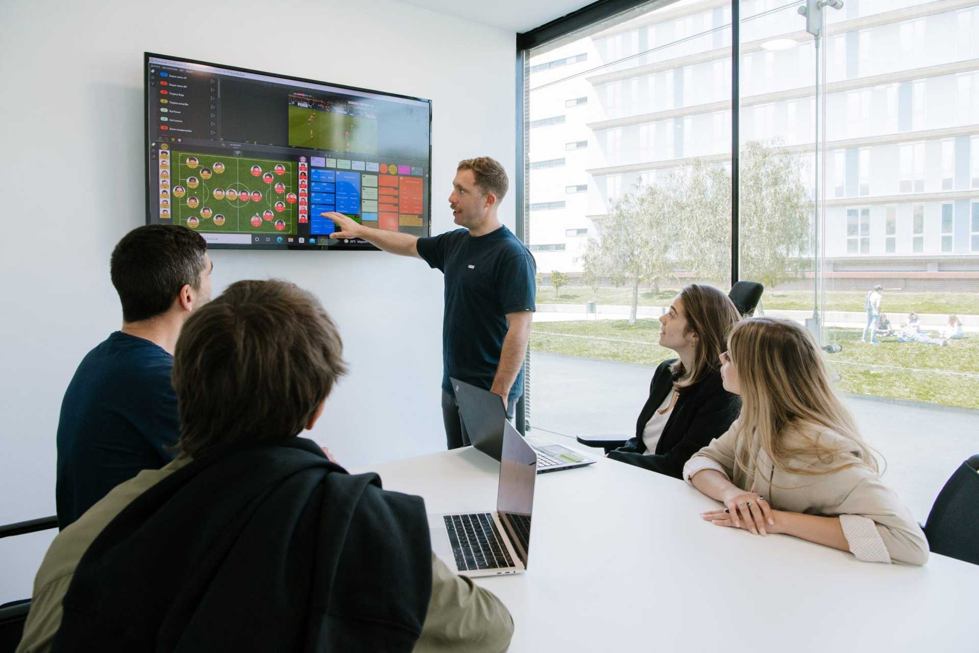 Team reviewing football video analysis with LongoMatch on a large screen