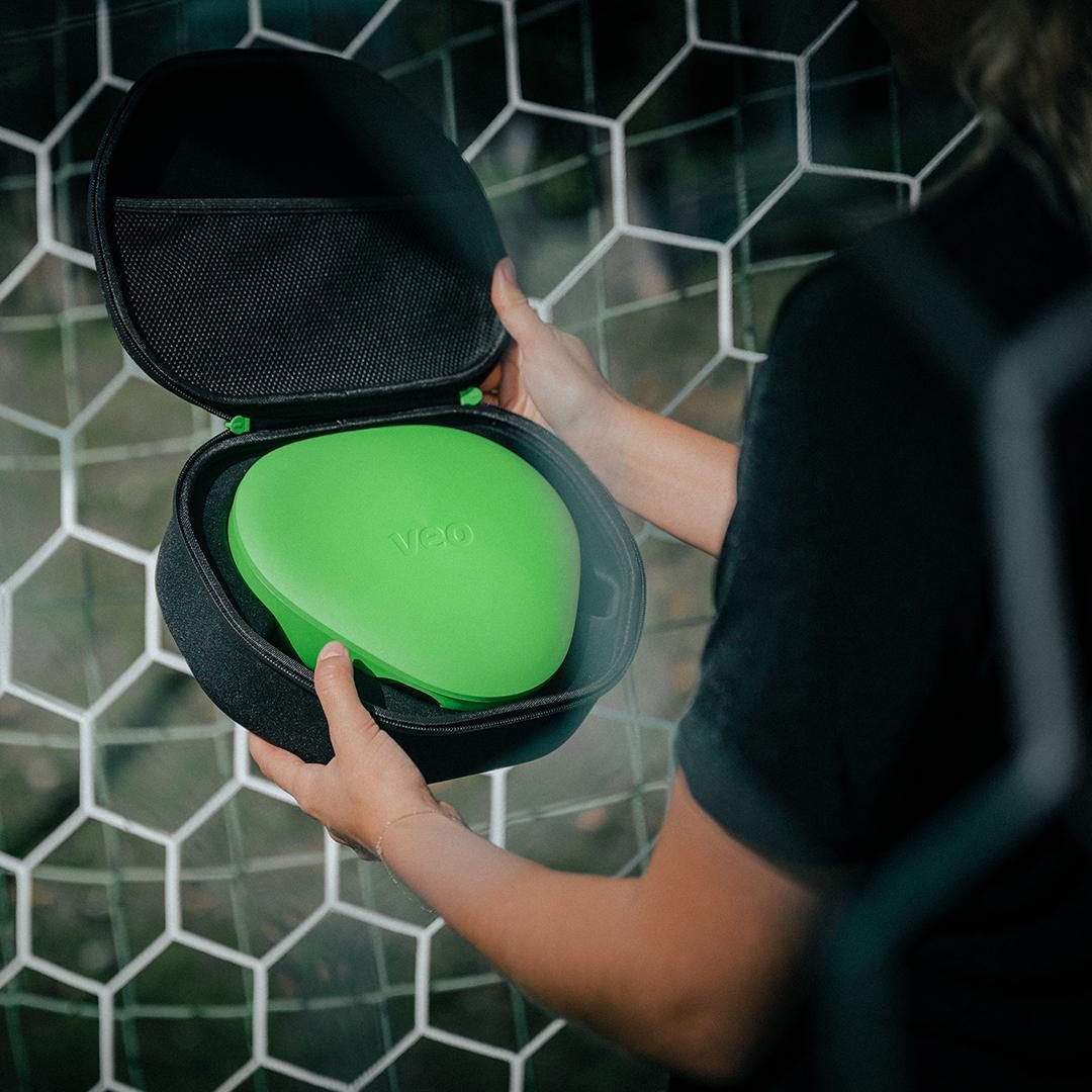 Veo sports camera in its protective carrying case beside a football goal